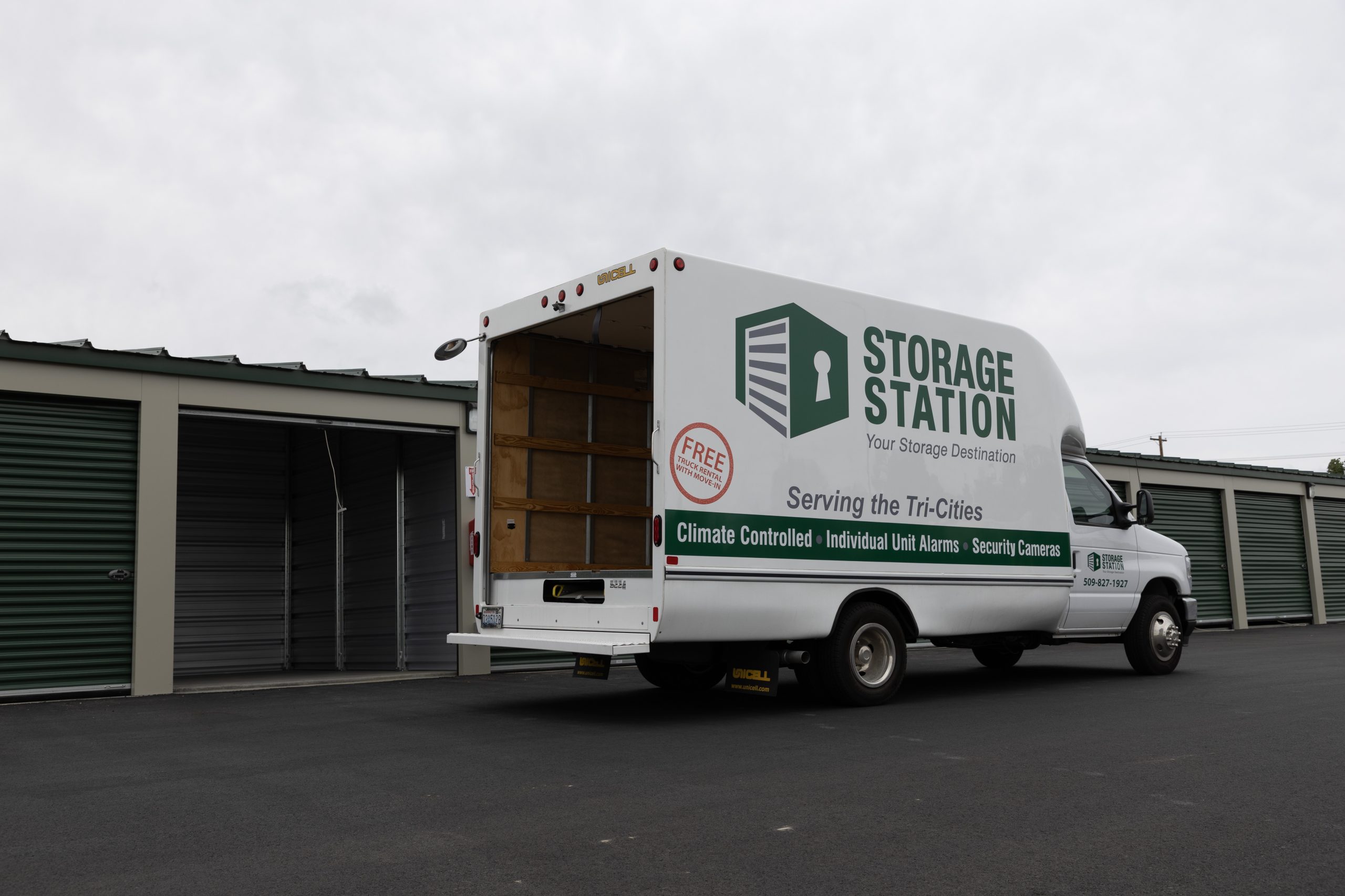 Storage station moving truck in front of units with its back open.